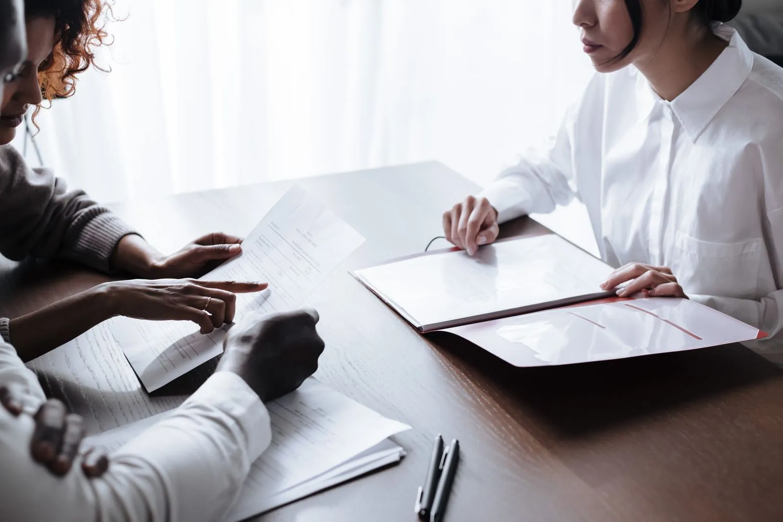 A consultant and clients reviewing printed business and funding documents together